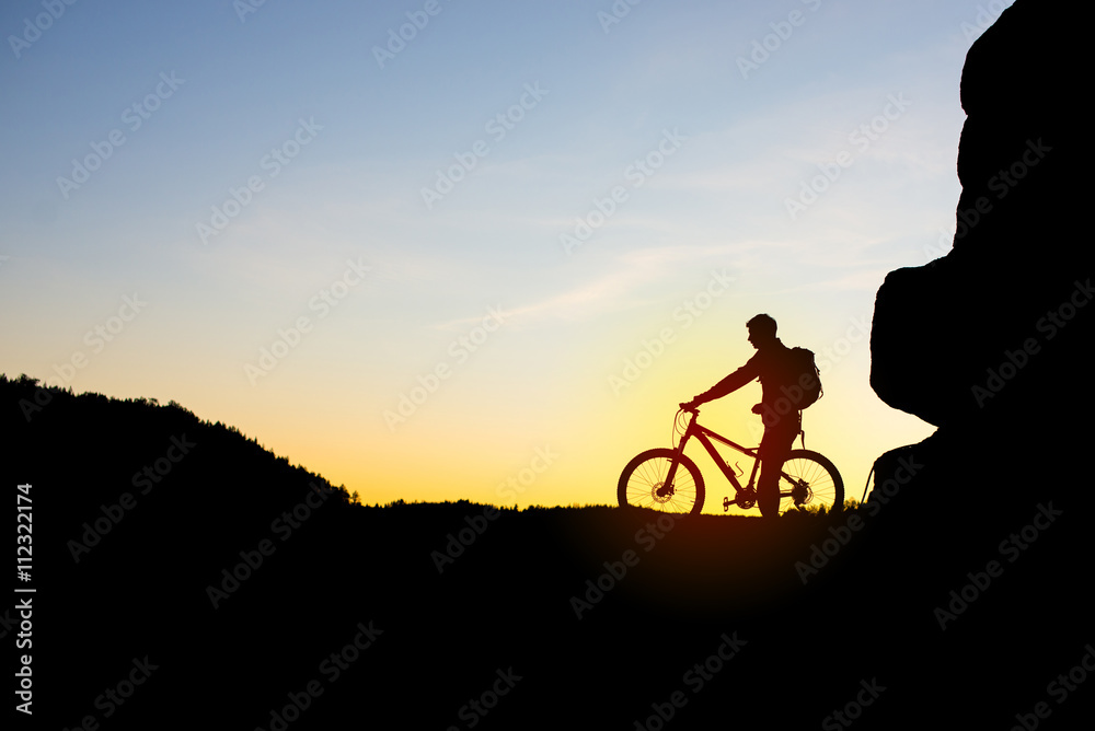 Silhouette of Cyclist with Bike on the Rock at Sunset. Silhouette of Cyclist with Bike on the Rock at Sunset.