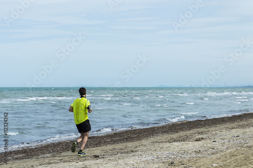 A young guy plays jogging on the beach