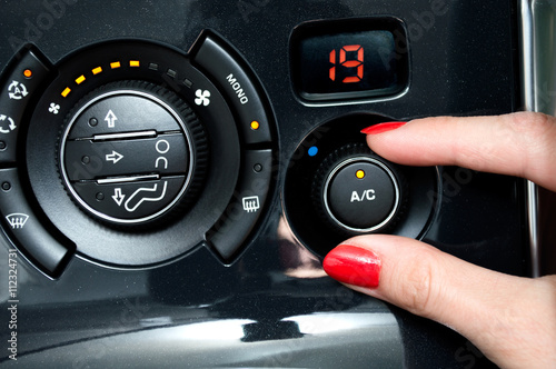 Woman turns on air conditioning in a car photo