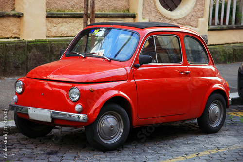 funny red small old little italian car with round headlights and