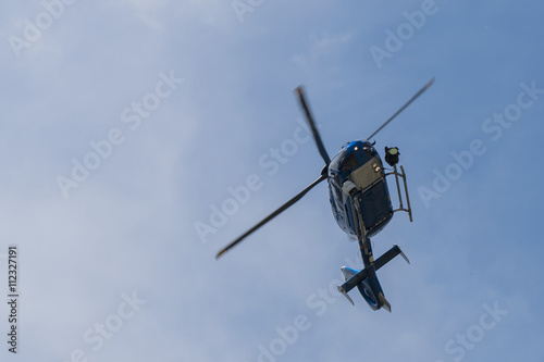 Police helicopter on blue sky flying and searching criminals.