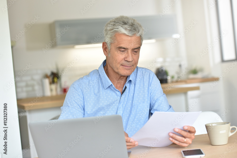 Smiling senior man at home using laptop Smiling senior man at home using laptop