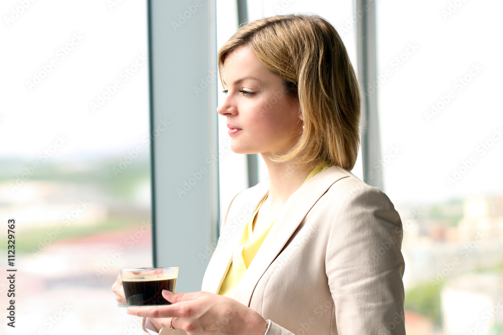 Portrait of business woman standing with coffee near window Portrait of business woman standing with coffee near window