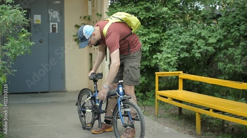 Man with beard folding bicycle near home