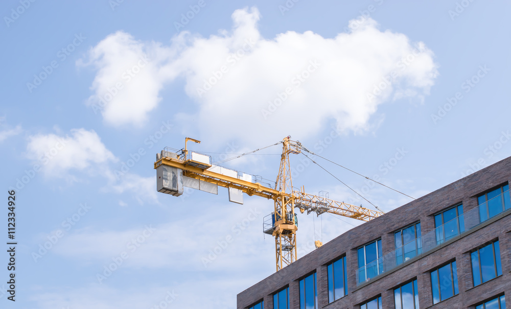 Construction crane and a building house against sky Construction crane and a building house against sky