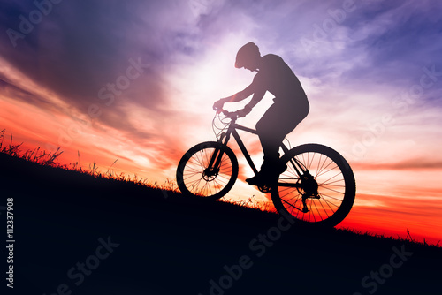 Fototapeta Naklejka Na Ścianę i Meble -  Silhouette of a biker on bike with sky background on sunset.