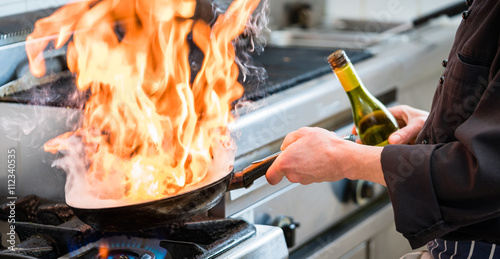 Chef doing flambe to food in pan with alcohol photo