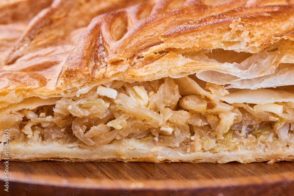 A piece of pie with filling their cabbage on wooden plate A piece of pie with filling their cabbage on wooden plate