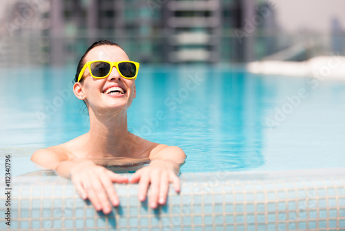 Happy people on vacation. Young woman enjoying a swim in the pool.