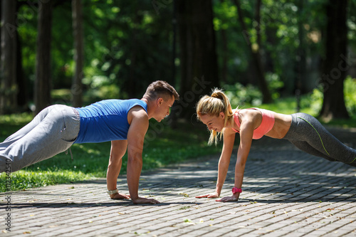 Cuadro en lienzo Couple doing push-ups at the park.Workout outdoors.