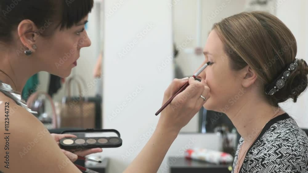 Makeup artist making make-up for young model Makeup artist making make-up for young model