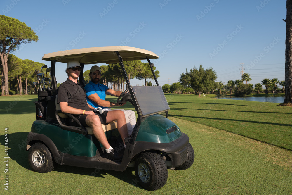 golf players driving cart at course