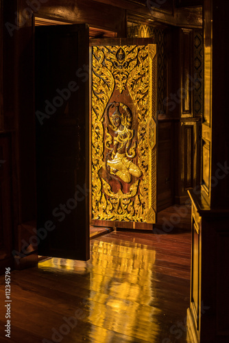 Beautifuly Wooden Door with Golden God carve texture at public worship - reflection on wooden floor