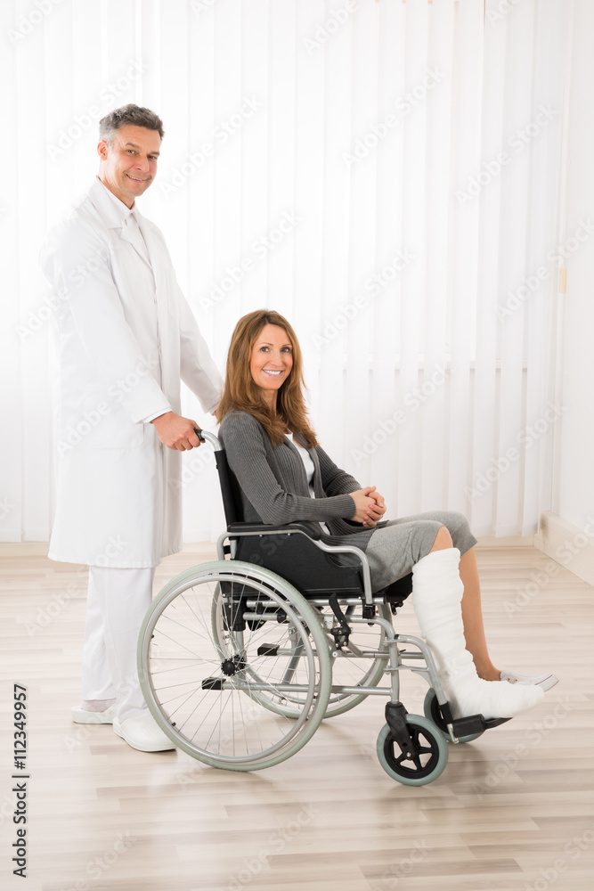 Doctor Assisting Woman On Wheelchair
