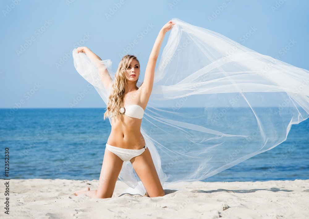 Elegant, attractive woman in alluring swimwear posing on the bea