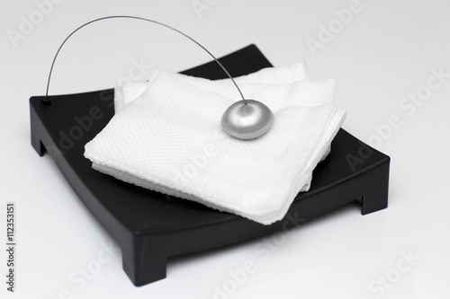 Stand for napkins on a white background. Black napkin holder with metal clip filled with white napkins. 