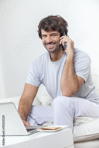 Man working on laptop and talking on phone