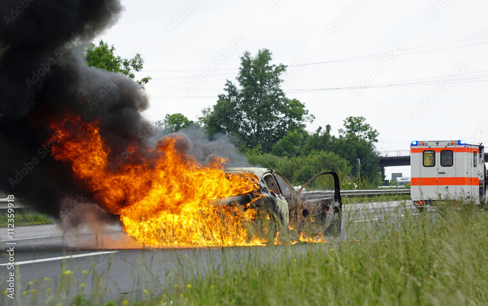 Fototapeta premium Ein Auto brennt lichterloh auf der Autobahn