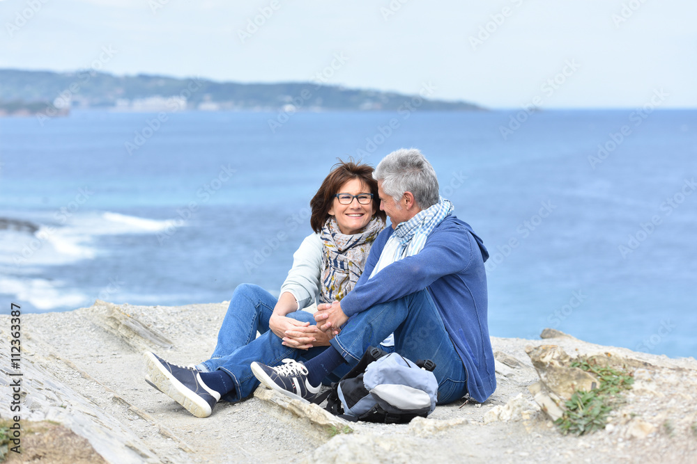 Senior couple on rambling day sitting by cliff