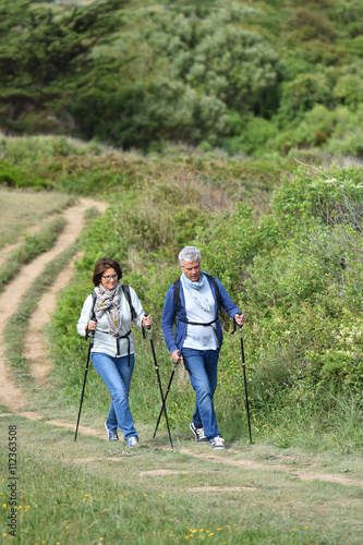 Senior couple walking on hiking track by the coast