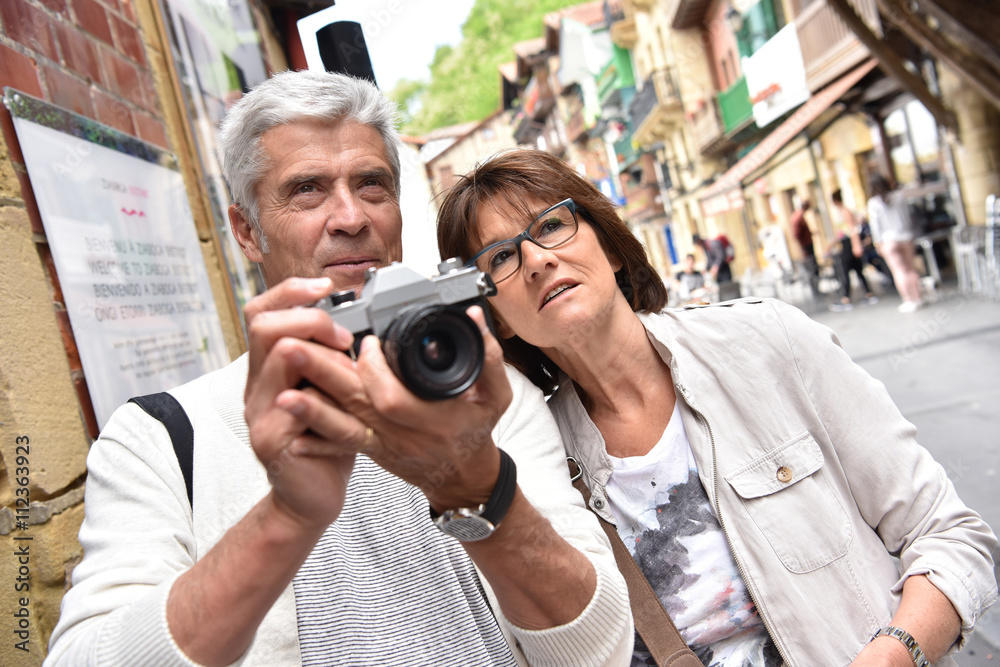 Senior couple of tourists taking pictures during tour