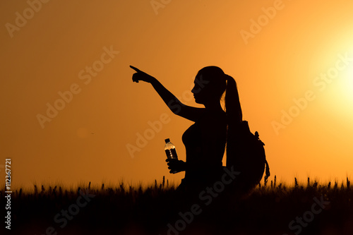 Woman hiker standing in wheat field at sunset