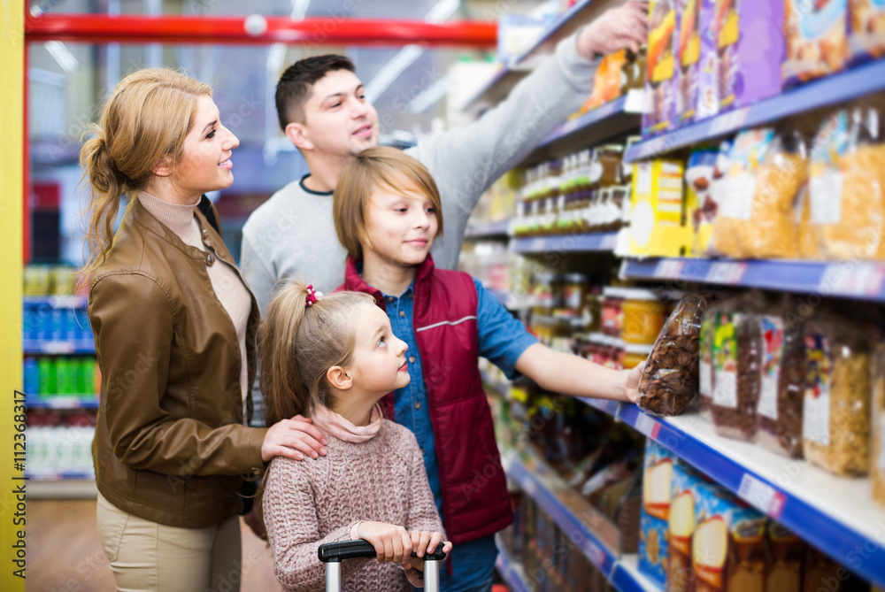 Parents with two kids choosing crispy flakes in shop
