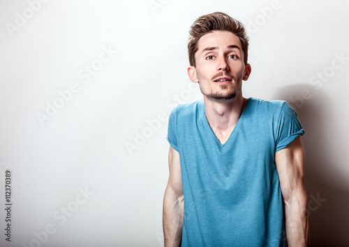 Studio portrait of young handsome man in casual turquoise t-shirt.