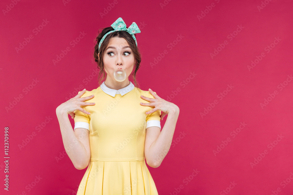 Cute playful pinup girl doing bubble with chewing gum