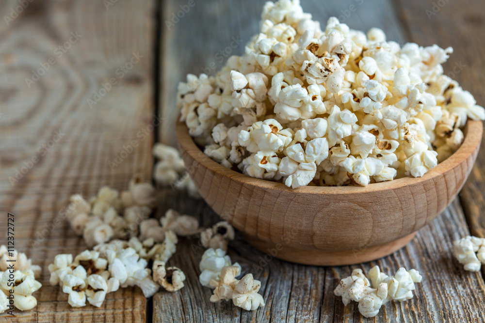 Popcorn in wooden bowl closeup.