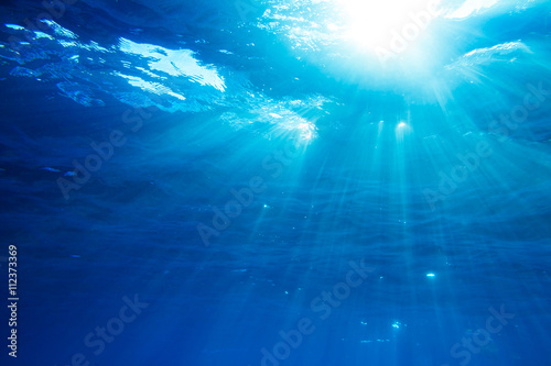 Underwater shot with sunrays in deep blue tropical sea
