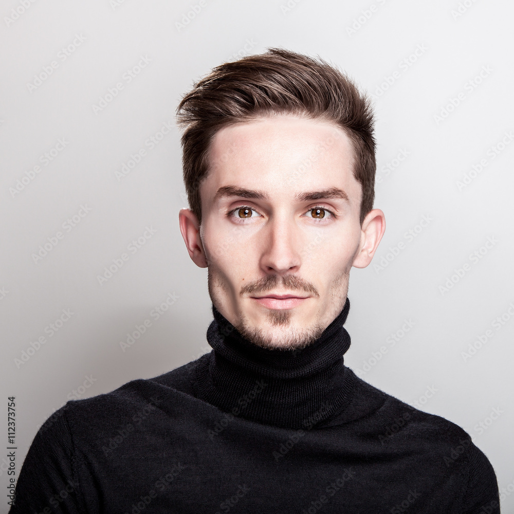 Fotografie Attractive elegant man in black golf posing on light gray background