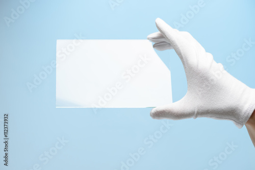 Hand in glove holding rectangular piece of transparent material, new features of glass or plastic research