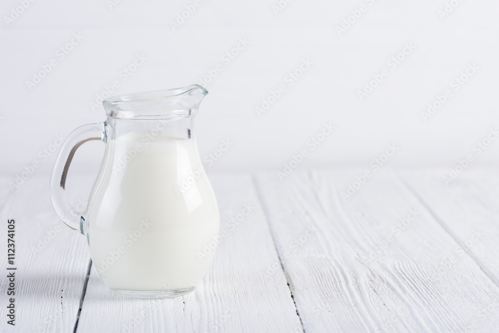 Jug of milk on white wooden table still life