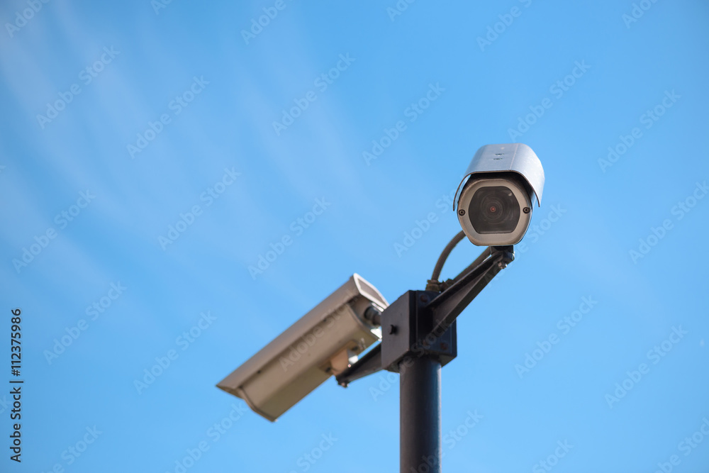 CCTV surveillance cameras on pillar mount over blue sky background CCTV surveillance cameras on pillar mount over blue sky background