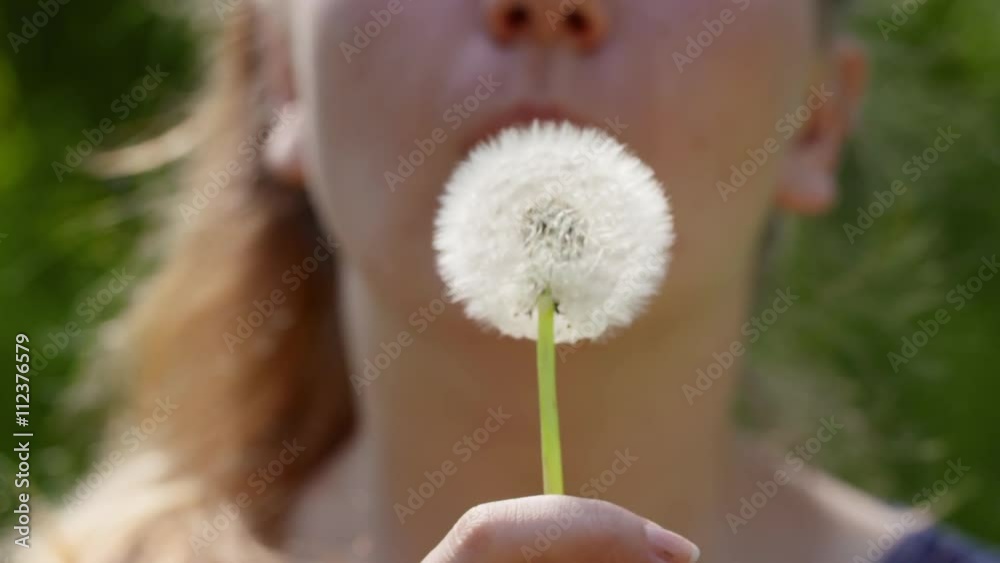 teen girl blowing white dandelion to the camera on sunny day slowmo, 180fps prores footage