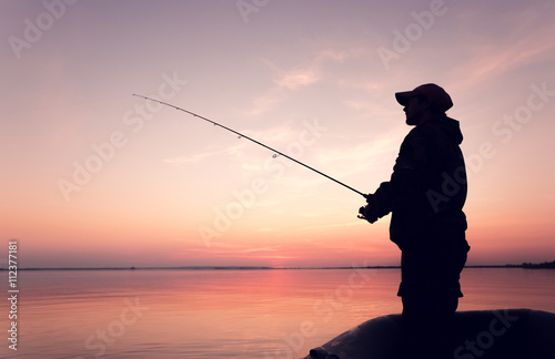 Silhouette man in a boat with a fishing rod