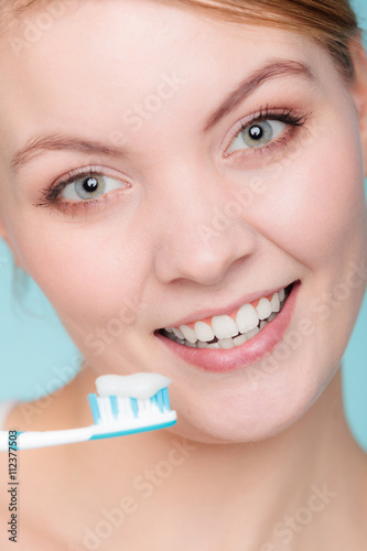 woman holds toothbrush with toothpaste cleaning teeth