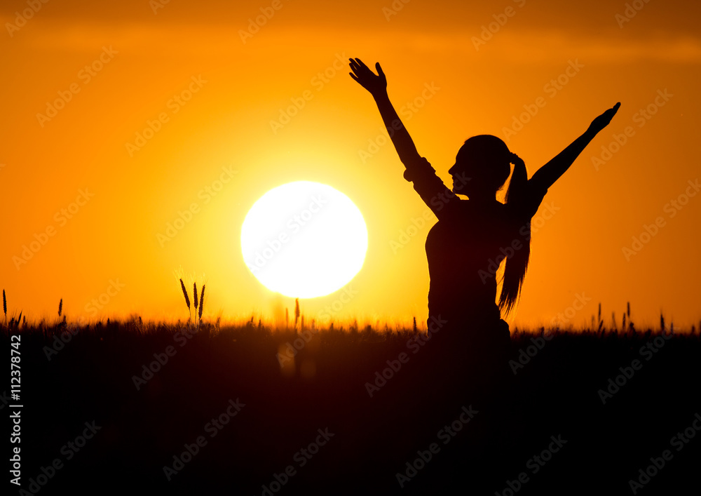 Silhouette of girl with raised hands at sunset Silhouette of girl with raised hands at sunset