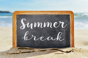 text summer break in a chalkboard, on the sand of a beach