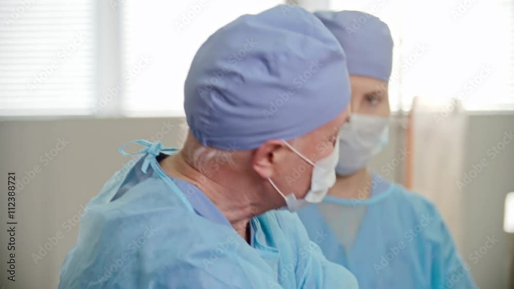 Experienced senior surgeon receiving forceps from female assistant at operation, shot on Sony NEX 700 + Odyssey 7Q Experienced senior surgeon receiving forceps from female assistant at operation, shot on Sony NEX 700 + Odyssey 7Q