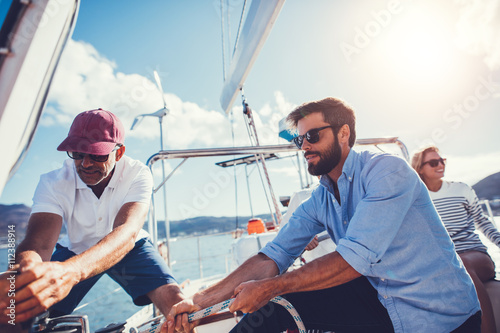 Two men pulling rope on yacht photo