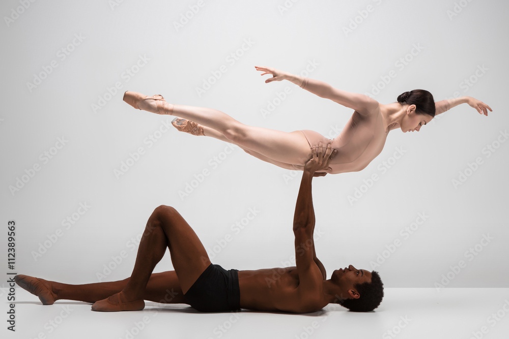 Naklejka premium Couple of ballet dancers posing over gray background