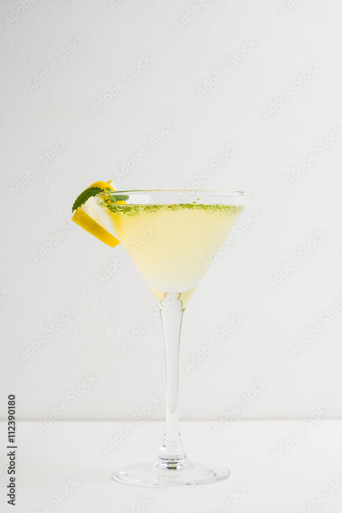 Yellow martini cocktail with lemon and mint on the rustic wooden background