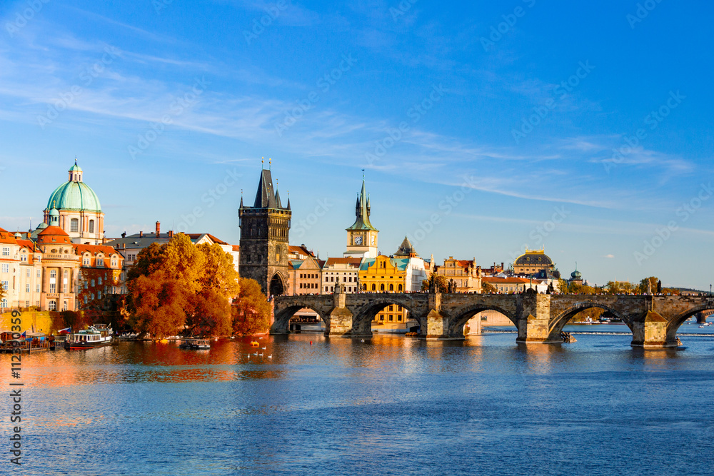 Fototapeta premium View of the Vltava River and Charle bridge with red foliage, Prague, Czech Republic