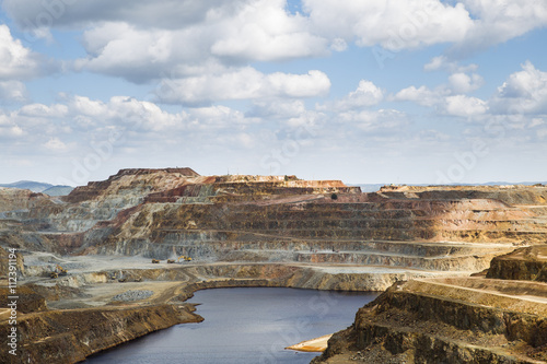 View on rocky stone landscape with water under bright sky in sunlight, opencast mining