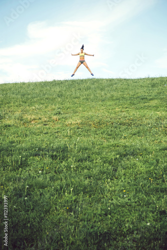Sporty woman running over a small hill against the skyline photo