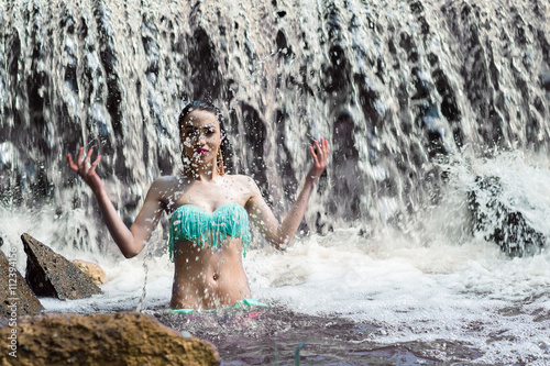 attractive woman splashes water on waterfall
