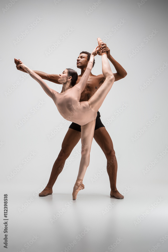 Fototapeta premium Couple of ballet dancers posing over gray background
