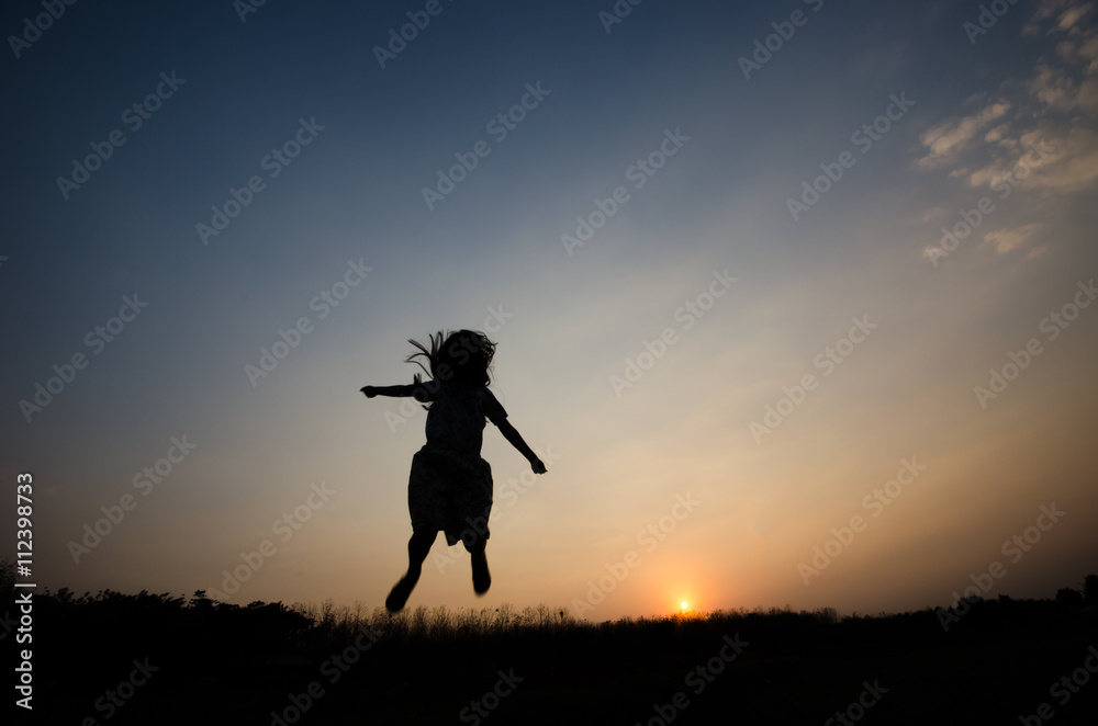 Silhouette of a girl gesture happy with the golden light of the sunset,